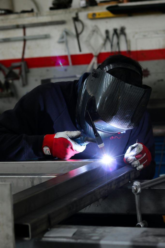 A skilled welder works in a Treviso workshop, focusing on precision metalwork.